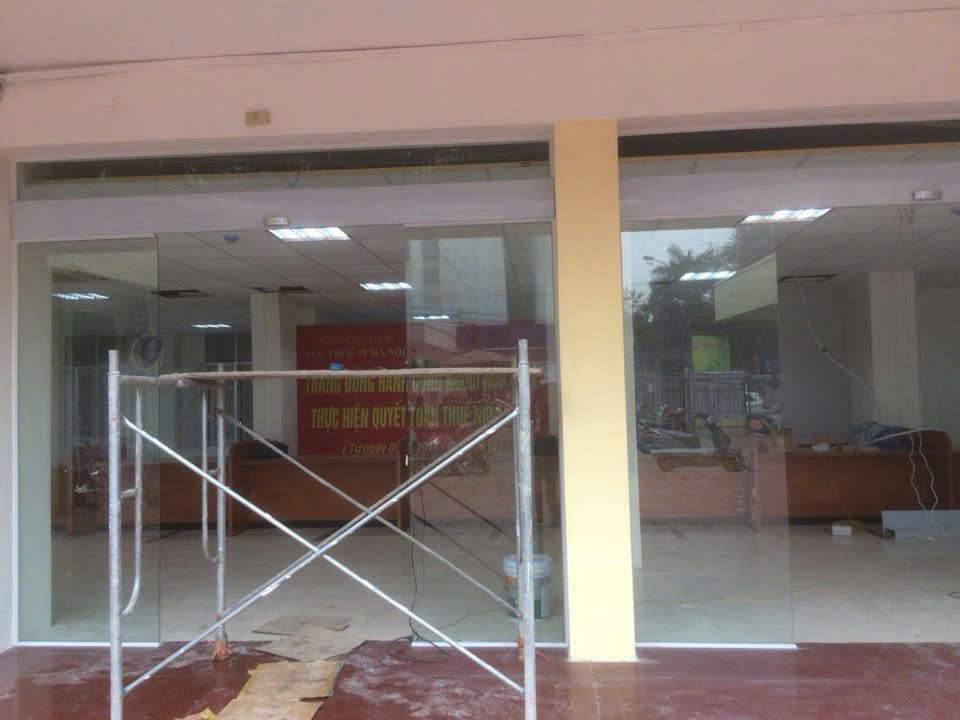 Cửa kính cường lực mặt tiền văn phòng đang thi công với giàn giáo phía trước